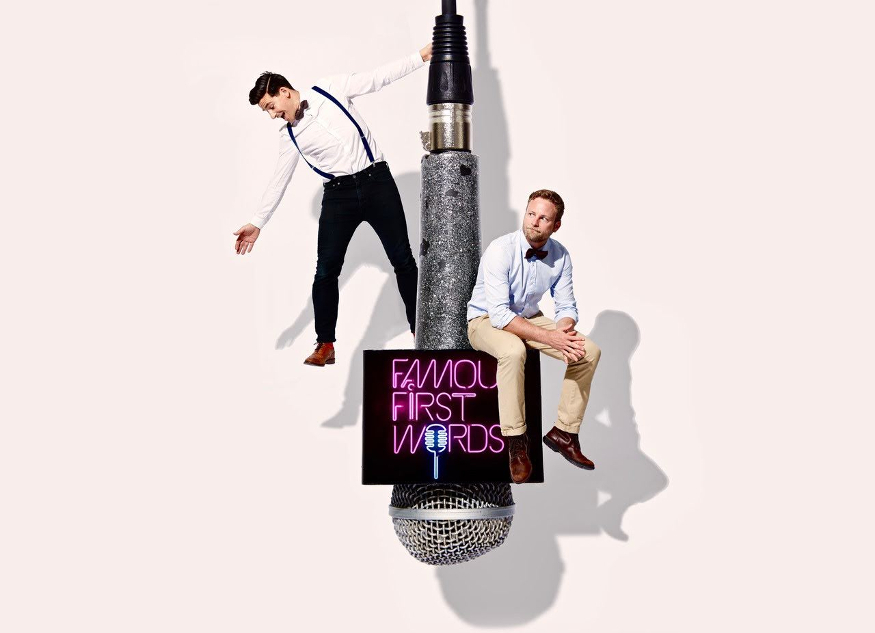 Two men posing on a giant hanging microphone.