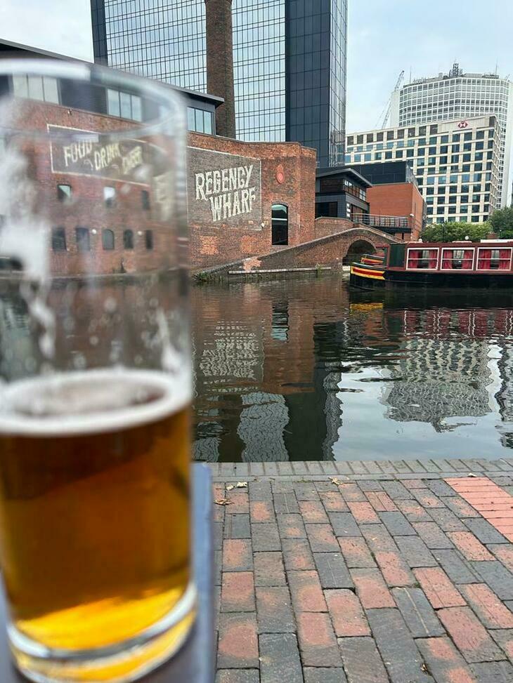 A pint of beer in front of a canal with a narrowboat on it