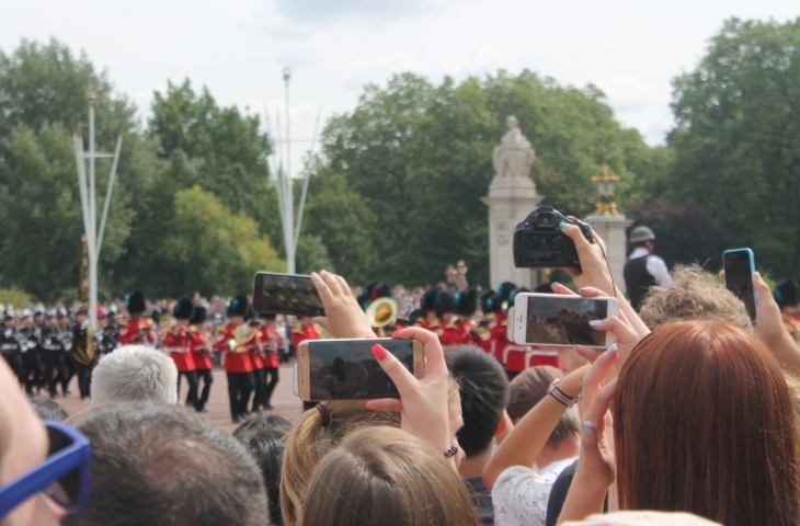 people hold phones aloft to film marching soldiers down the mall