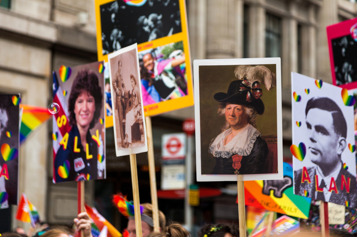 Various placards with pictures of pioneering LGBTQ people on them