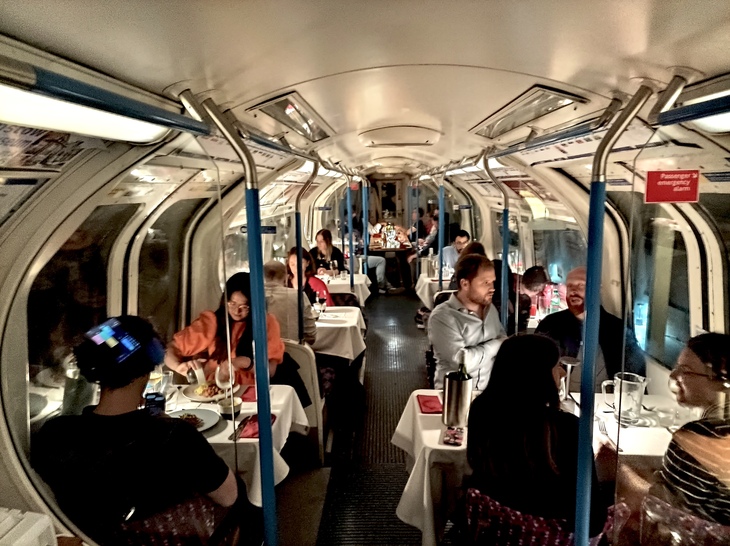 Tube Supperclub:  People eating at tables on a tube train