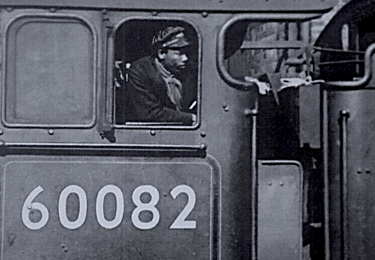 Black History Month London: Britain's first black train driver: a Black man leans from the cab of a steam train