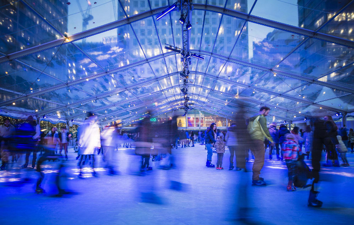 People ice skating on a rink inside a giant conservatory