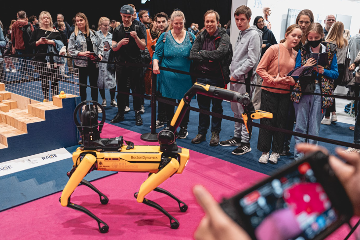 People looking at a yellow and black robot 